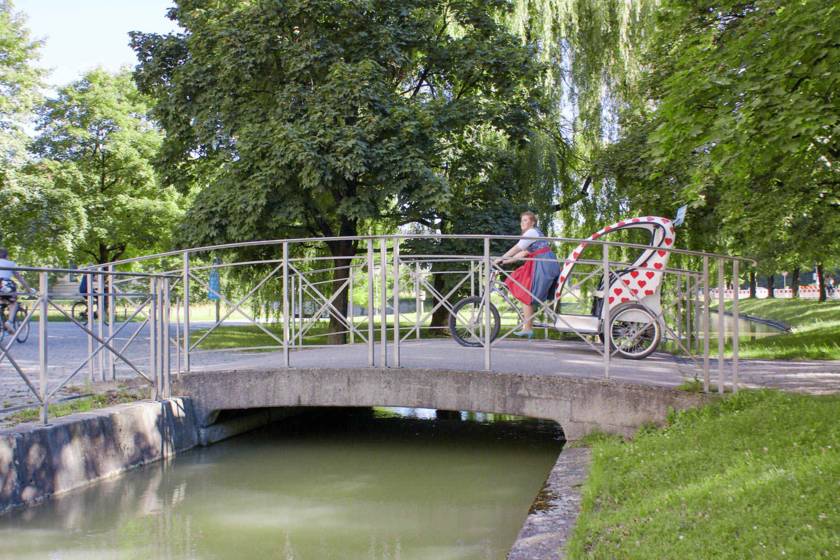 Rikscha überquert Brücke im Englischen Garten