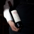 Ein Kellner von Geisels Vinothek hält eine Flasche Wein in der Hand