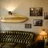 Gemütliche Sitzecke im True Brew in München mit Ledercoach, Vintage-Lampe und Bildern und einem Surfbrett an der Wand darüber