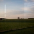 Blick aus dem Zug auf weite Felder in der Abendsonne.