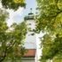 Der Kirchturm der St. Georg im Stadtteil Bogenhausen rankt zwischen Bäumen hindurch