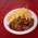 Ein Teller Currywurst mit Pommes steht auf einem roten Tisch