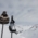 Zwei Skistöcke mit Wollmütze stecken im Schnee vor einem winterlichen Bergpanorama.