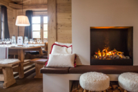 A cozy interior with a set table and a fireplace in the middle.