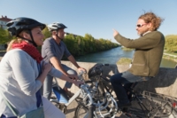 Drei Fahrradfahrer unterhalten sich auf einer Br&uuml;cke an der Isar in M&uuml;nchen.