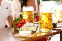 Zwei Masskr&uuml;ge mit Bier und einem B&uuml;ndel Radieschen auf einem Tisch in einem M&uuml;nchner Biergarten.