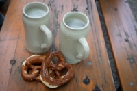Due boccali di birra e due pretzel su un tavolo di legno.