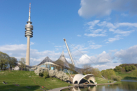 Der Olympiapark M&uuml;nchen im Fr&uuml;hling mit gr&uuml;nen Wiesen und bl&uuml;henden B&auml;umen.