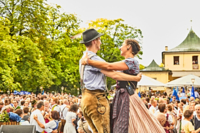 Ein Paar in Tracht tanzt auf einer B&uuml;hne zusammen. Im Hintergrund sind weitere Paar die gemeinsam tanzen.