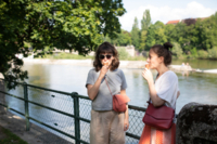 Zwei Frauen essen Eis an der Isar in M&uuml;nchen.