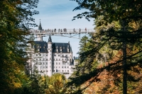 The picturesque Neuschwanstein Castle, framed by an autumnal forest with changing colours of the leaves.