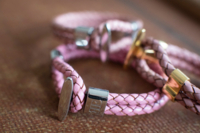 Ein pinkes Armband der Marke Enzo Escoba liegt auf einem braunen Untergrund.