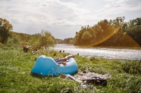 A young man lies on an air mattress in summer on the Isar river in Munich