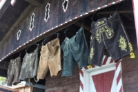 Verschiedene Lederhosen h&auml;ngen an einer Holzh&uuml;tte.