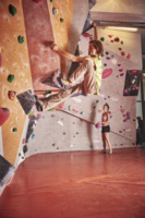 A man bouldering around an element on a ledge in a bouldering hall.