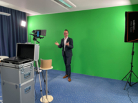 Ein Mann steht vor einer Greenwall und redet in die Kamera.