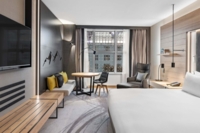 Blick in ein Hotelzimmer mit Bett, TV, Lounge