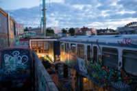View at dawn over spray-painted, discarded railway wagons and shipping containers belonging to Bahnw&auml;rter Thiel area in Munich..