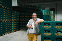 Steffen Marx steht vor Bierkisten der Giesinger Brauerei in M&uuml;nchen mit einer Flasche Bier in der Hand.