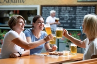 Tre turisti brindano con boccali di birra.