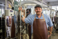 Ein Braumeister der Haderner Bio-Brauerei steht an einem Bier Lagertank in der Produktionshalle.