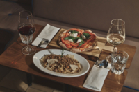 Eine Pizza und ein Pastagericht stehen auf einem Tisch in der Riva Bar in M&uuml;nchen.