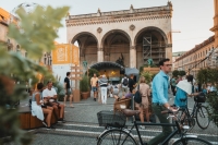 Feldherrnhalle mit B&uuml;hne im Rahmen der Stadtoase im Hintergrund, im Vordergrund sitzen Menschen oder fahren mit dem Fahrrad vorbei.