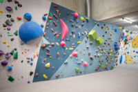 In einer Kletterhalle befindet sich eine Boulderwand mit verschieden bunten Steinen