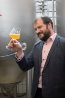 Ein Mann h&auml;lt ein Glas mit Bier in der Hand und betrachtet dieses.