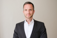 Prof. Dr. Christoph Spinner, Facharzt f&uuml;r Innere Medizin und Infektiologie steht vor eines wei&szlig;en Wand und l&auml;chelt.