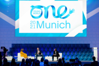 Drei Personen diskutieren auf dem Podium des One Young World Summit in M&uuml;nchen.