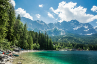 A man sits on the shore of the Eibsee and looks up at the Zugspitze.