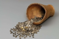 Celtic silver coins flow from a broken ceramic vessel.