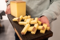 Bei einer F&uuml;hrung durch die M&uuml;nchner K&auml;semanufaktur wird K&auml;se auf einem Holzbrett gereicht