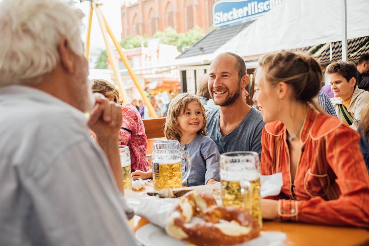 Eine Familie mit Kind trinkt Bier auf der Auer Dult in M&uuml;nchen.