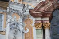 Detailansicht der Fassade der Asamkirche mit Säulen, Stuckaturen und einem Relief von Papst Benedivćt XIII