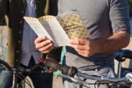 Ein Mann mit Fahrrad hält einen München-Prospekt in der Hand.
