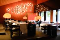 Innenansicht des Restaurants Tantris in München mit der typischen 70er-Jahre Einrichtung mit großen Stehlampen und roten Wänden.