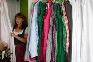 Eine Frau im Dirndl schaut aus einer Umkleidekabine im Trachtengesch&auml;ft Bavarian Outfitters in M&uuml;nchen heraus.