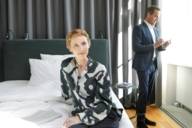 Eine Frau sitzt in einem Hotel in München auf einem Bett. 