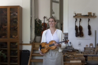 Die Geigenbauerin Katharina Starzer steht in ihrer Werkstatt mit einer Geige in den Händen