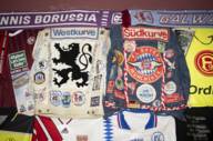 Historische Fußball-Fanartikel wie eine Jacke vom FC Bayern München mit verschiedenen Stickern und eine Jacke von 1860 München im gleichen Stil in München.