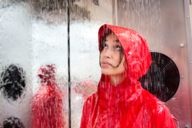 Frau steht mit einer Regenjacke bekleidet in einer Regenkammer im Geschäft Globetrotter in der Münchner Innenstadt.