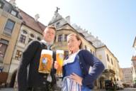 Junger Mann mit Maß Bier und junge Frau mit Weißbier vor dem Hofbräuhaus in München
