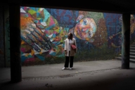 Junge Frau steht vor einem Mural in München.