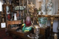Antike Statuen und Vasen stehen inmitten von Antikmöbeln und alten Lampen