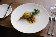 Ein Gericht mit Zucchiniblüte auf einem weißen Teller im Restaurant Brothers in München. Daneben liegt Besteck.