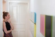 Eine junge Frau betrachtet Bilder in einer Galerie in München.