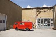 Ein alter roter Kleinbus der Feuerwehr steht vor einem Werksgebäude im Münchner Kreativquartier.