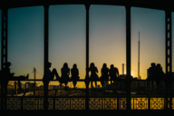 Menschen sitzen auf der Hackerbrücke in München und betrachten den Sonnenuntergang.